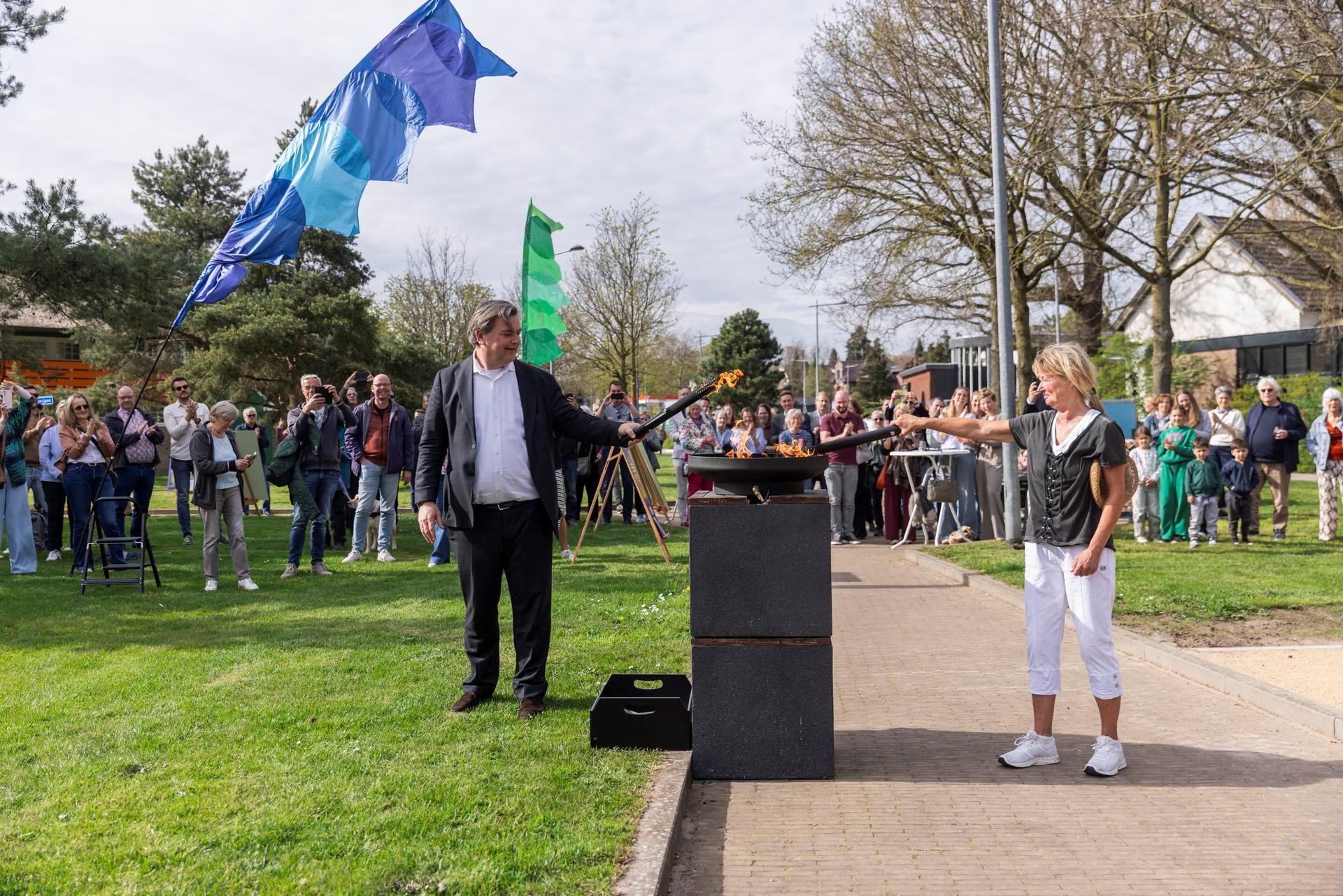 Wethouder Floris Voorink en buurtbewoonster Erna Bot ontsteken symbolisch een Olympische vlam.  