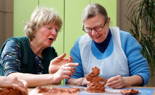 Guide and visitor working on clay together
